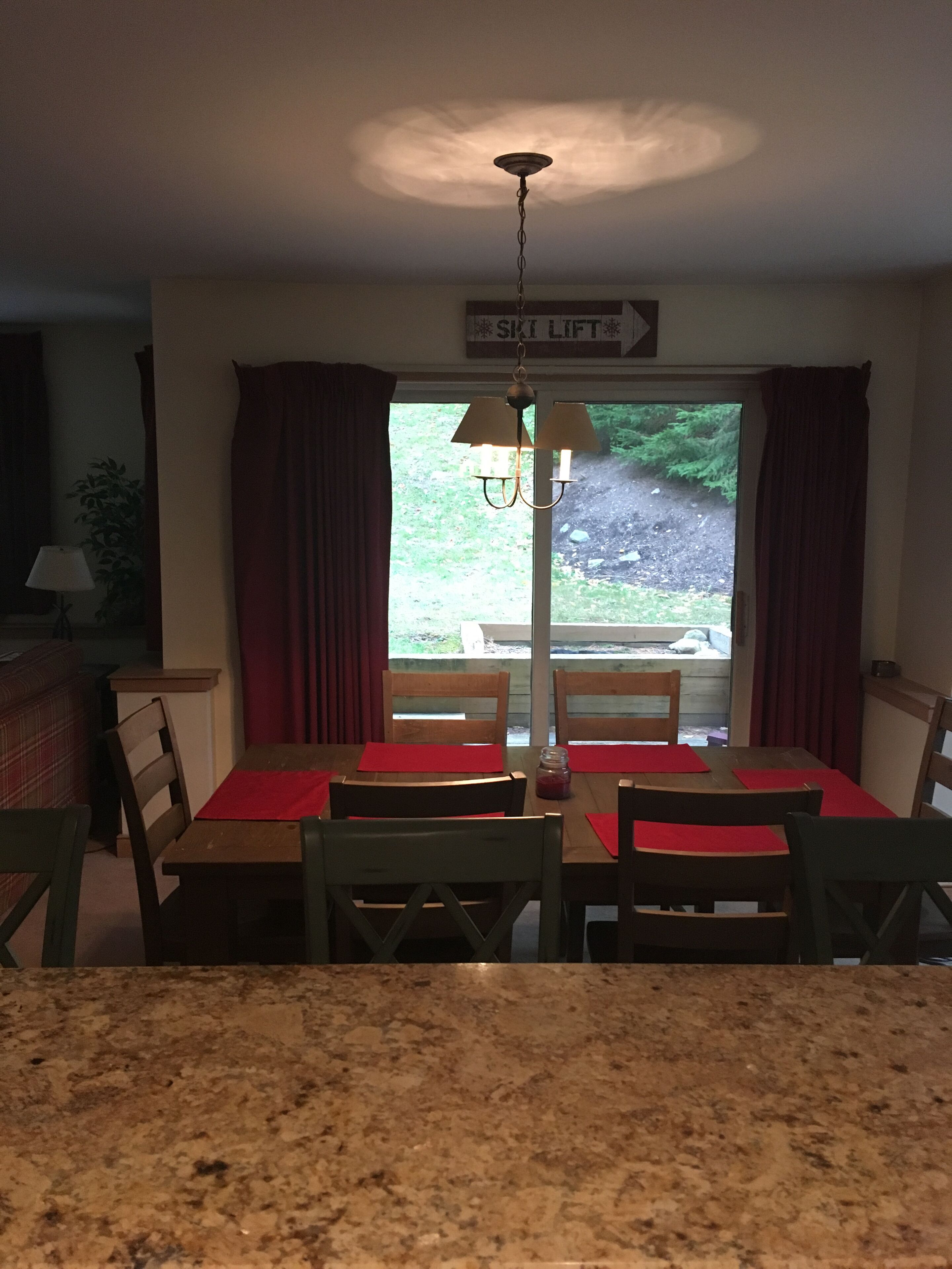 Un comedor con encimera de granito, sillas de madera y una araña.