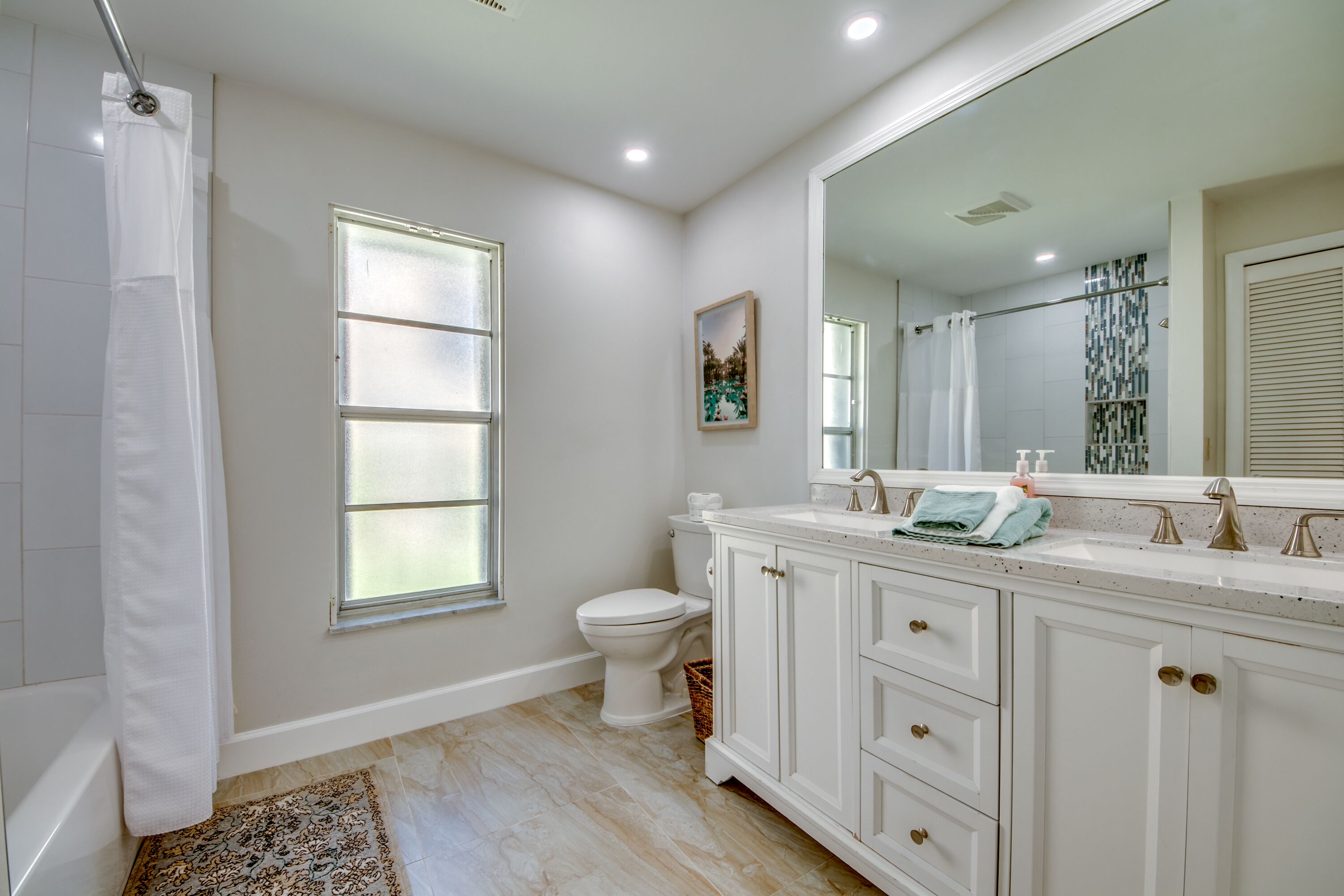 A bathroom with a toilet, a sink with a large mirror, and a shower curtain.