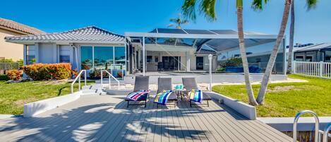 A modern outdoor deck with lounge chairs and a pool area.