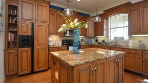 Cocina con gabinetes de madera, encimeras de granito y una isla central.