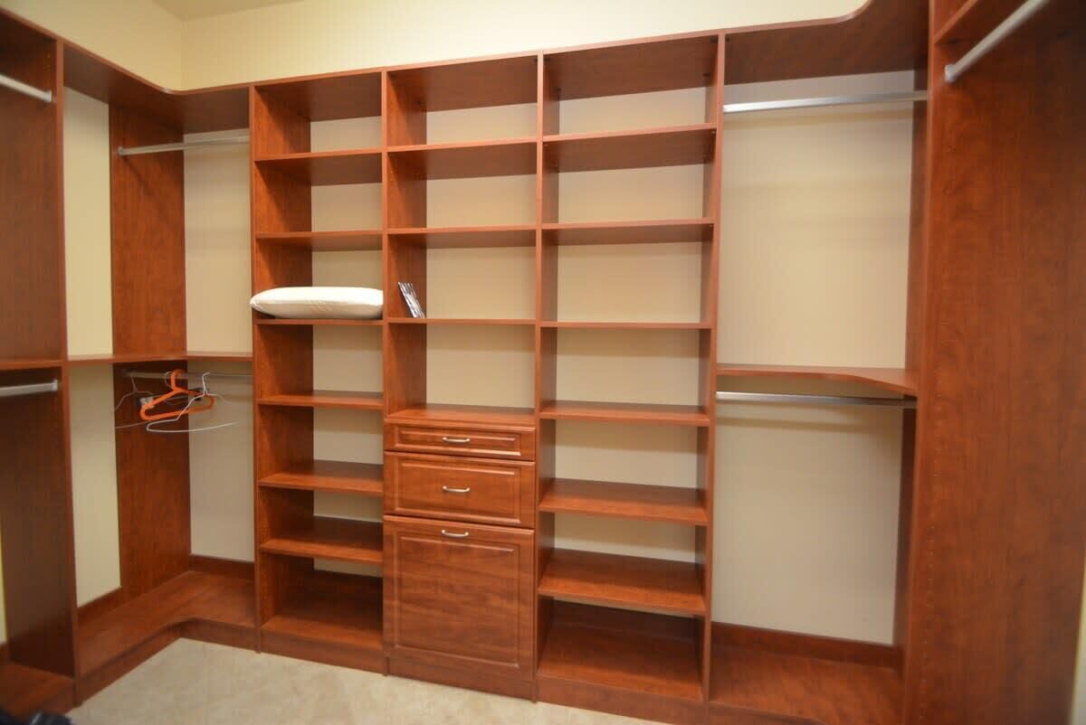 Ein begehbarer Kleiderschrank mit mehreren Regalen und Schubladen, einer Kleiderstange und einem Schuhregal.