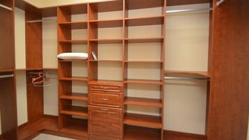 Ein begehbarer Kleiderschrank mit mehreren Regalen und Schubladen, einer Kleiderstange und einem Schuhregal.