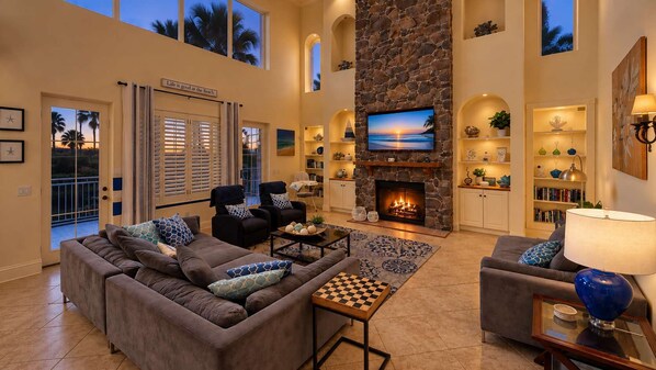 Amplia sala de estar con chimenea, asientos cómodos y televisor.