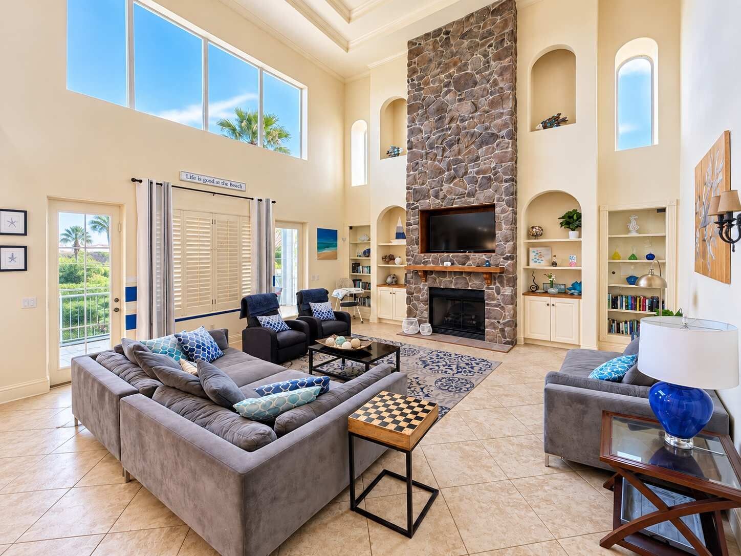 A spacious living room with a stone fireplace, a large sofa, and a television.
