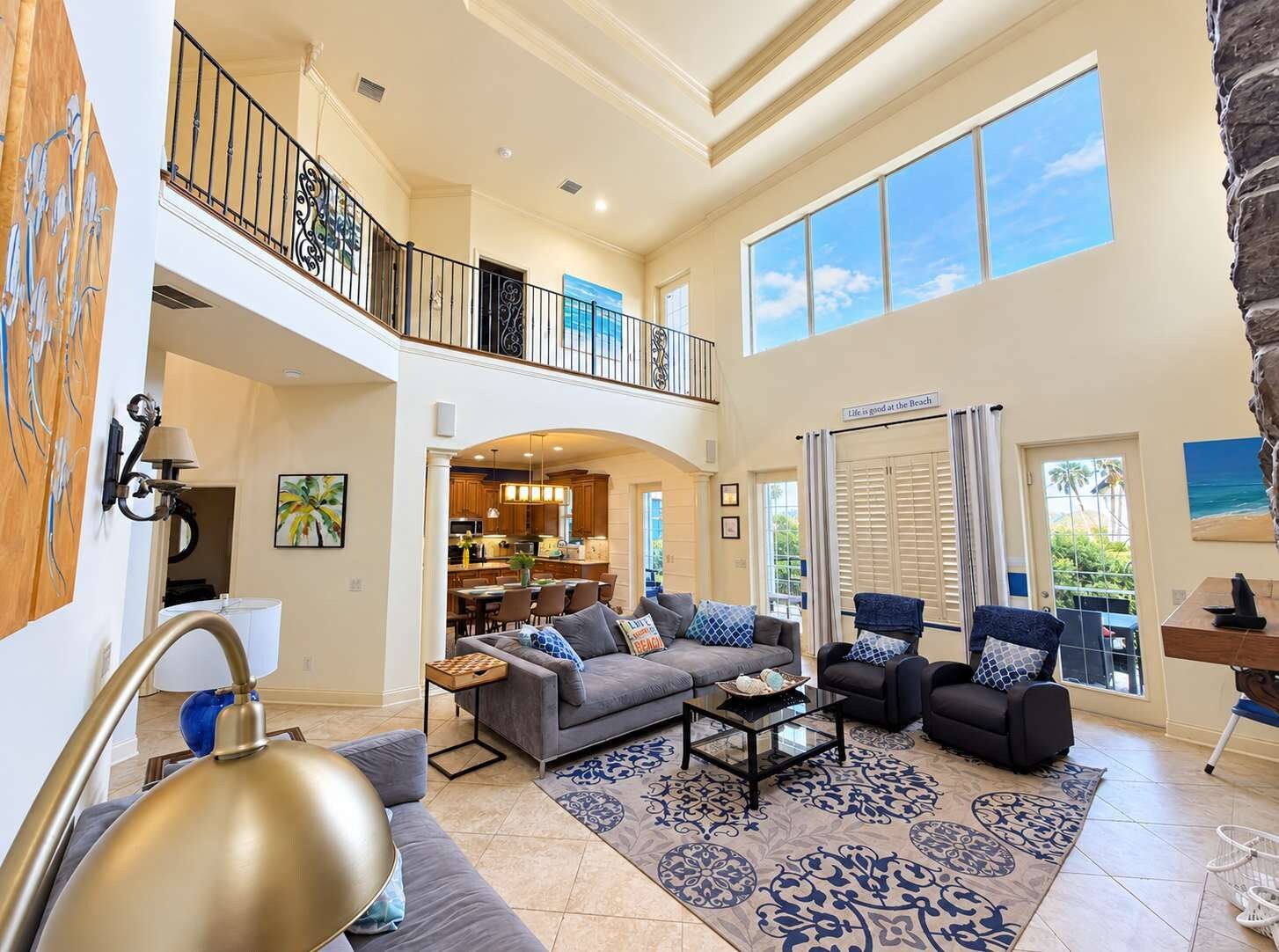 A spacious living area with a high ceiling, a dining area, and a kitchen.