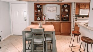 A kitchen with wooden cabinets, a white countertop, and a sign that reads "Welcome to our Beach House." - Cozy beach unit setup for vacations with kids or Couples!  (St Simons Island)