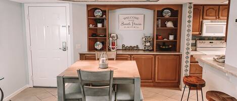A kitchen with wooden cabinets, a white countertop, and a sign that reads 'Welcome to our Beach House.'