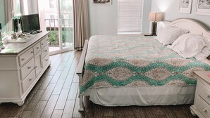 A bedroom with a bed, dresser, and a ceiling fan. - Cozy beach unit setup for vacations with kids or Couples!  (St Simons Island)