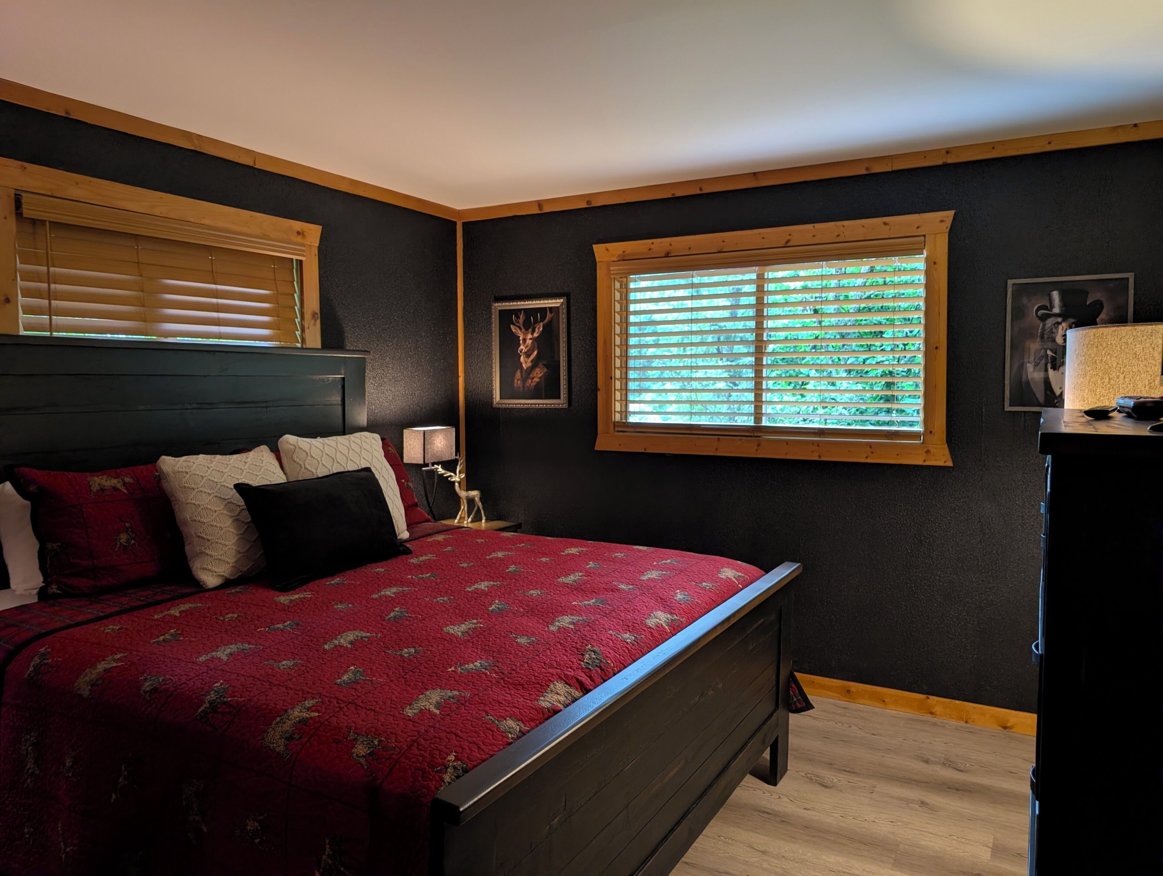 Une chambre à coucher avec un lit, une fenêtre avec des stores, une table de chevet et une lampe.