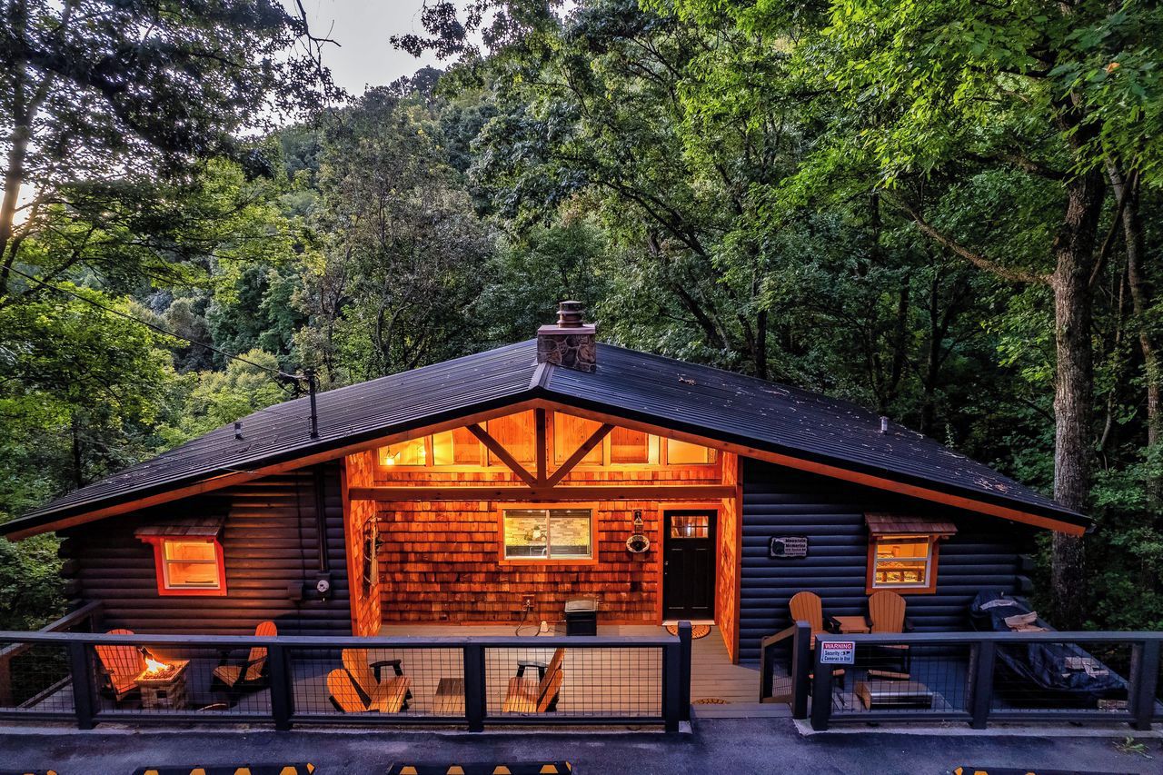 A log cabin with a porch, a fireplace, and a window.