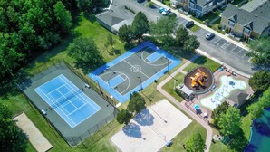 Vue aérienne d’un quartier résidentiel avec un terrain de basket, une aire de jeux et des maisons.