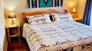 A bed with a patterned quilt, two bedside lamps, and a wooden headboard. - Vacation Townhome - Hot Tub, Red Rock Views, Walk to Dining/Trails (Sedona)