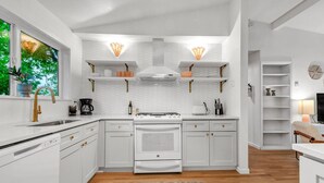 Una cocina moderna con armarios blancos, estufa integrada y un amplio ventanal.