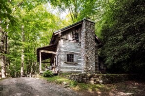 A rustic cabin with a stone chimney, wooden exterior, and a porch area. - Historic Creekside Cabin with Luxury Amenities, WiFi, Fireplace, Private Trails (Robbinsville)