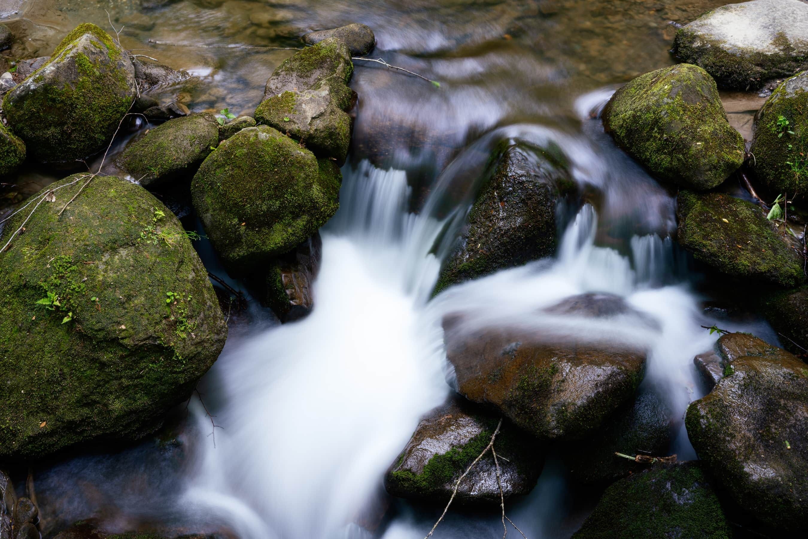 A stream flowing over rocks with moss.