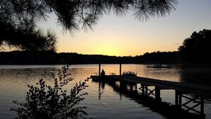 Una vista serena di un lago al tramonto, con un pontile che si protende nell'acqua.