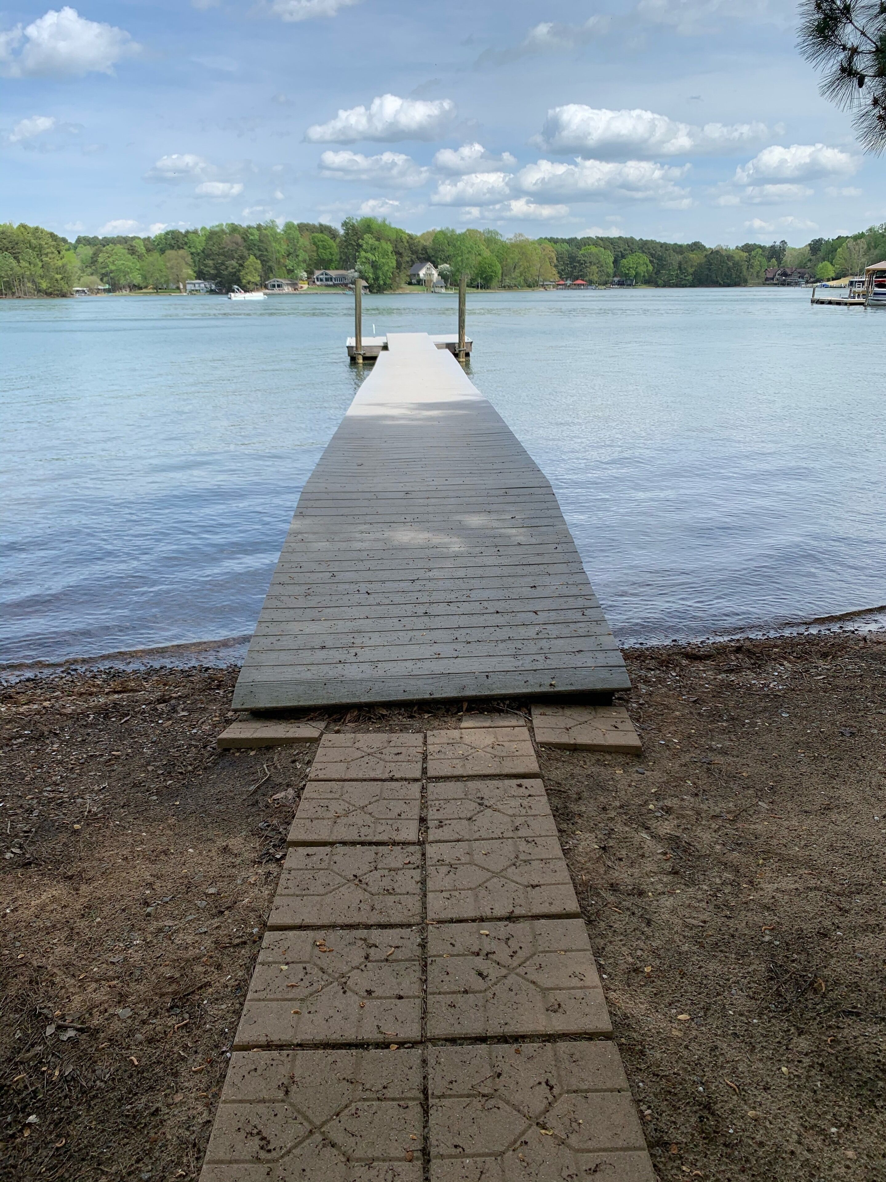 A wooden pier leading into a calm lake with a clear sky.