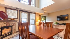 A dining area with a fireplace, wooden table, and chairs.