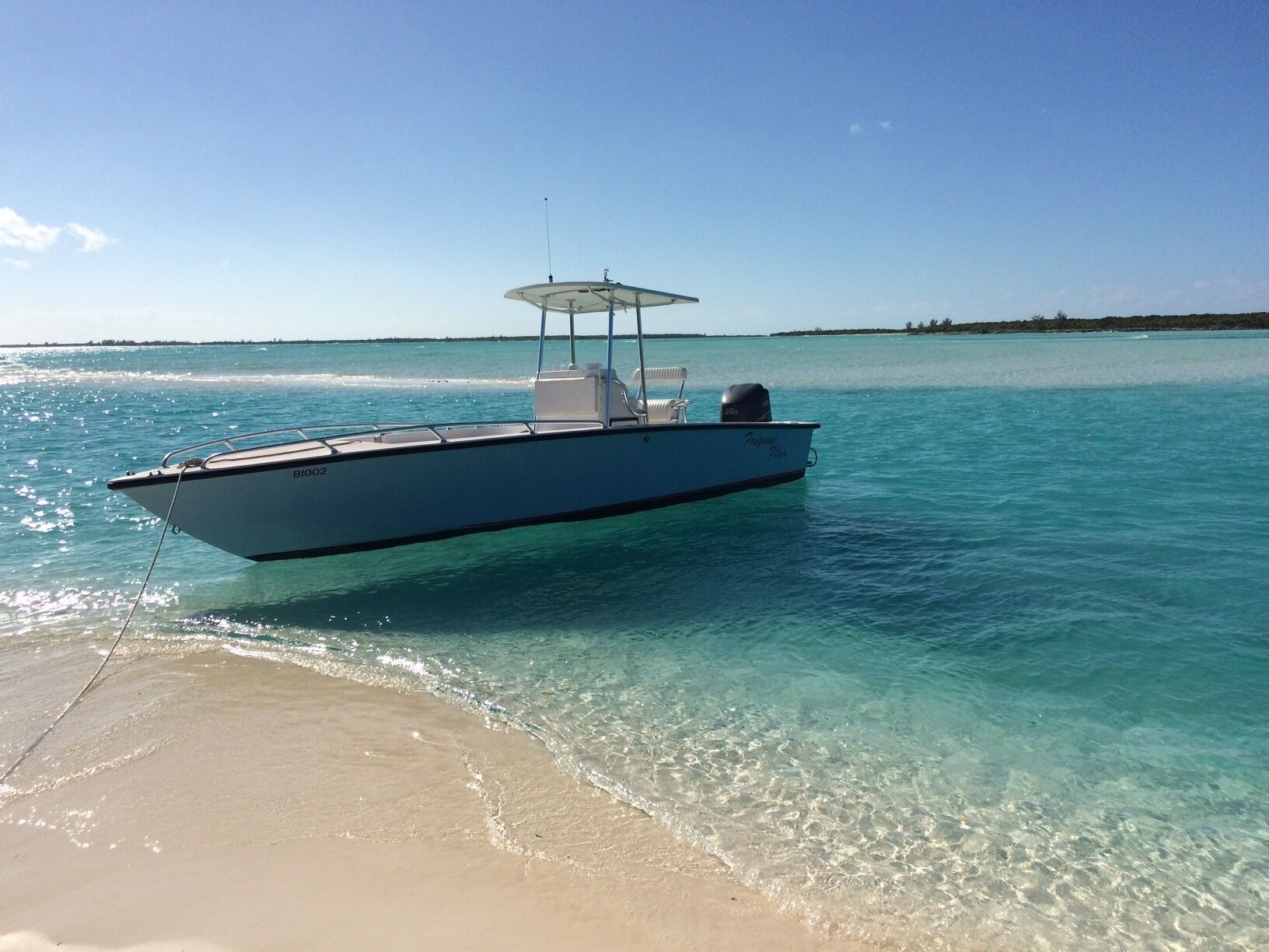 A boat named 'BIO2' on clear turquoise water near a sandy beach.