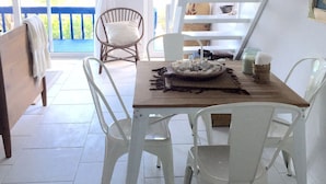 A dining area with a wooden table, white chairs, a wicker chair, and a view of the outdoors.