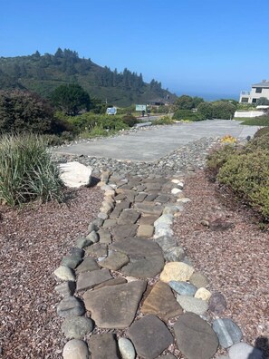 A pathway leading to a building with a view of a hill and ocean.
