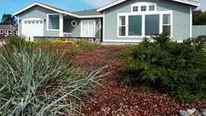 A two-story house with a garage, a covered patio, and a landscaped front yard with shrubs and a small garden. - Incredible Ocean Views 3 Bedrooms 3 Bathrooms (Trinidad)