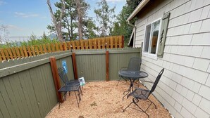 A backyard with a wooden fence, a patio table with chairs, and a small garden area.