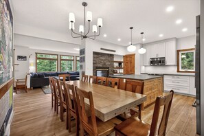 A modern kitchen with a central island, wooden dining table, and chairs.