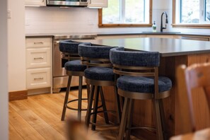 A kitchen with a bar area featuring stools and a stainless steel sink.