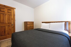 Une chambre à coucher avec un lit, une armoire en bois et une table de chevet.