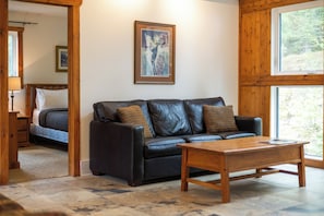 Une pièce avec un canapé en cuir noir, une table basse en bois et un tableau encadré accroché au mur.