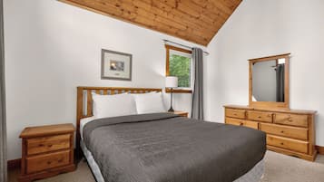 Une chambre à coucher avec un lit en bois, une table de chevet, une commode, un miroir et une fenêtre avec des rideaux.