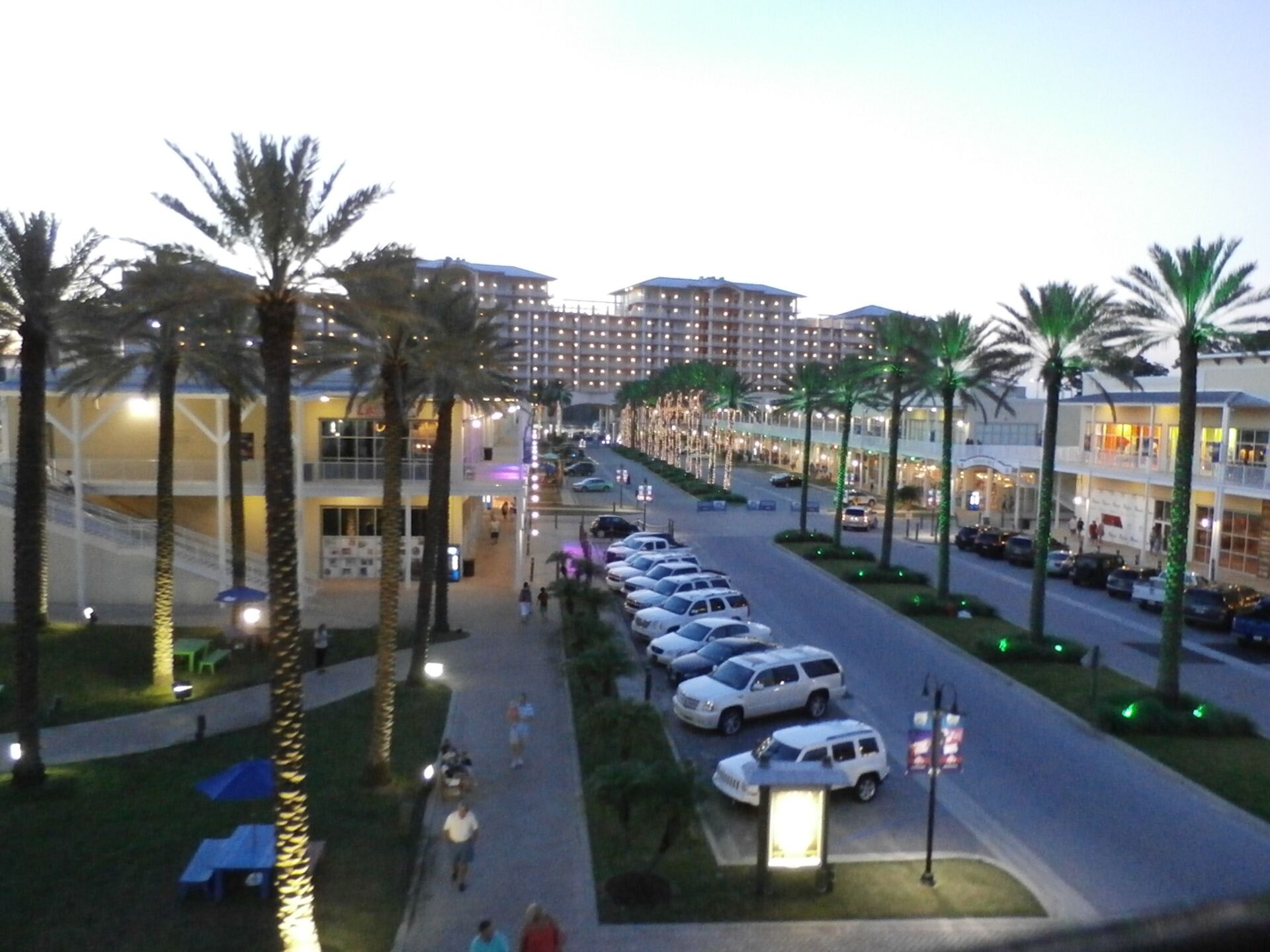 A hotel with multiple floors, a parking lot, and palm trees.