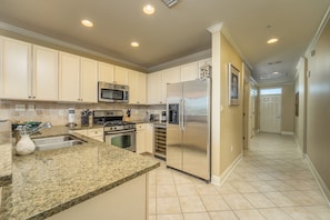 Cocina con encimeras de granito, electrodomésticos de acero inoxidable y armarios color beige.