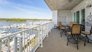 A balcony with a view of a marina, dining chairs, and a table.