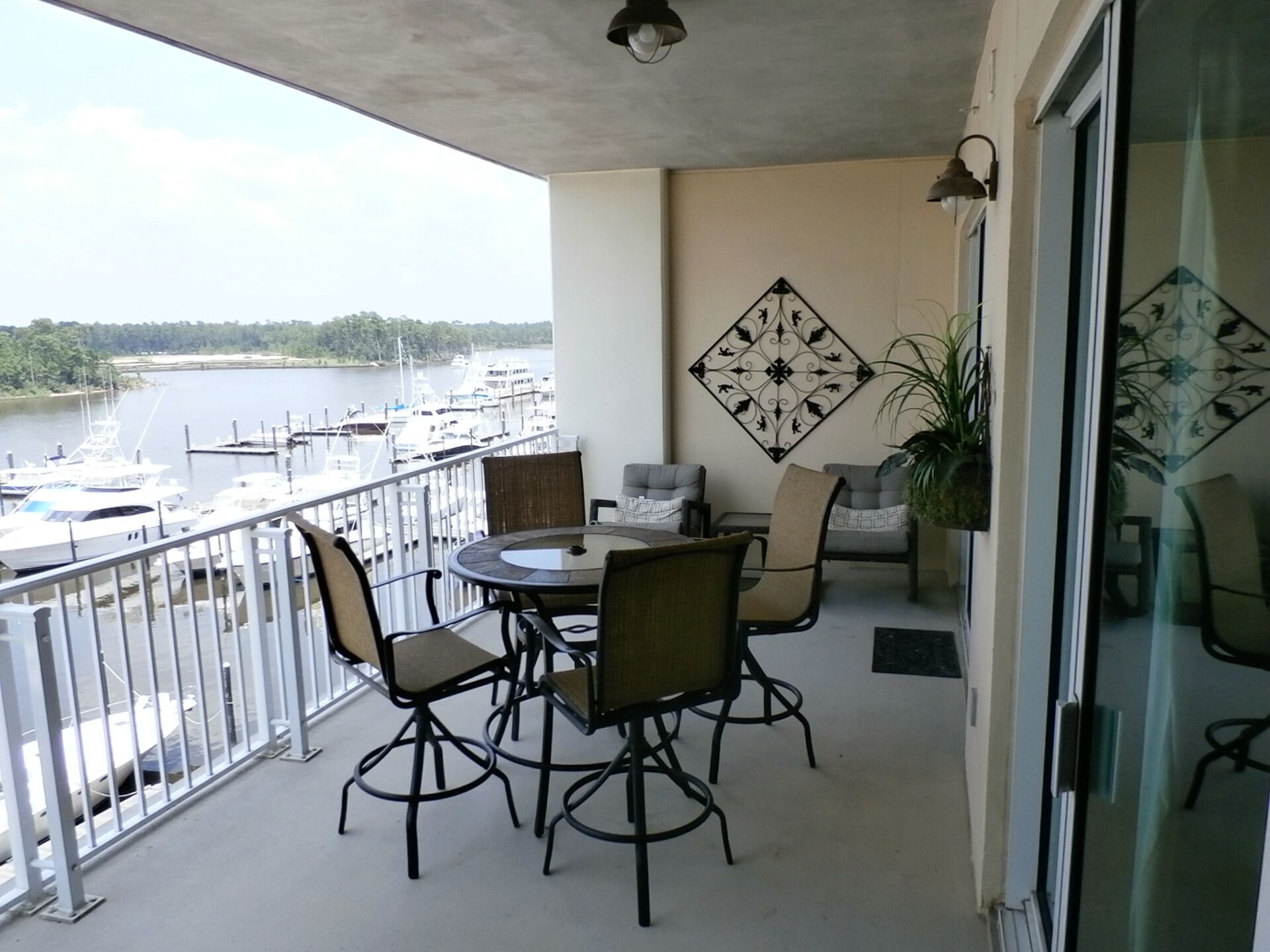 Un balcon avec une table et des chaises, donnant sur une marina où sont amarrés des bateaux.