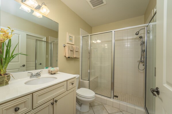 Une salle de bain équipée d’un lavabo, de toilettes et d’une douche à parois de verre.