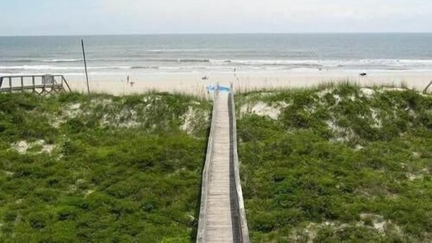 A boardwalk leading to a beach with a clear view of the ocean.