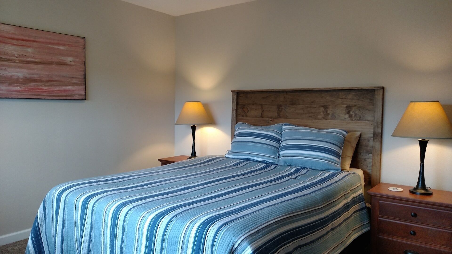 Ein Schlafzimmer mit einem Bett, zwei Nachttischen, einem Holz-Kopfteil und zwei Lampen.