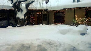A house with snow-covered ground and a car parked in front.