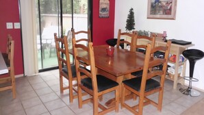 A dining area with a wooden table and chairs, a small candle, and a framed picture on the wall.