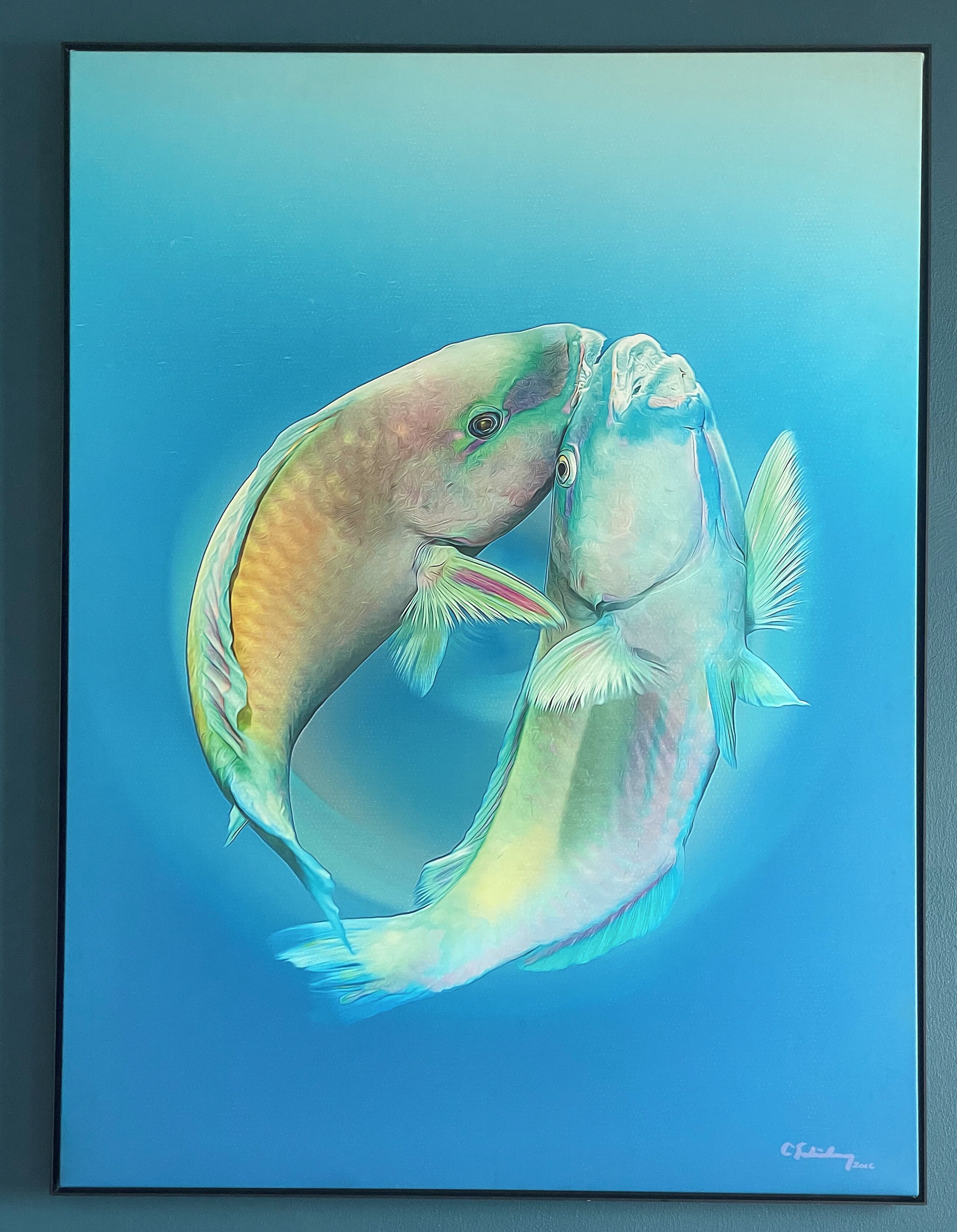 A framed painting of two fish intertwined, with a signature at the bottom right.
