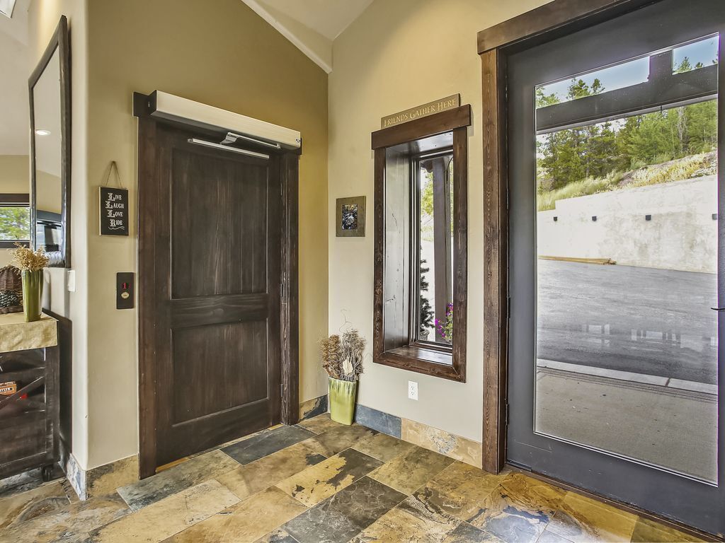 A hallway with a large wooden door, a small window, and a door with a sign reading "Friends Gather Here".