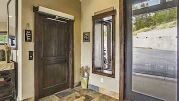 A hallway with a large wooden door, a small window, and a door with a sign reading "Friends Gather Here".
