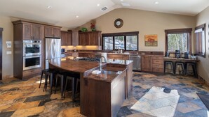 Une cuisine spacieuse avec des meubles en bois foncé, des appareils électroménagers en acier inoxydable et un grand îlot central doté de tabourets.