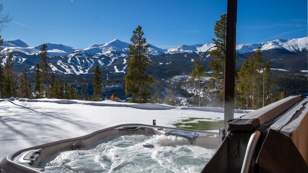 Un bain à remous avec un paysage enneigé et des montagnes en arrière-plan.