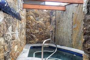 Ein Badezimmer mit Steinwänden, einer Badewanne und einer Duschkabine.