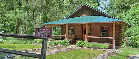 Un lodge rústico con techo verde, fachada de madera y un letrero que indica que es Cedar Mountain Lodge.