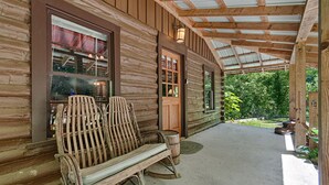 Eine Blockhütte mit überdachter Veranda, zwei Schaukelstühlen und einer Holztür.