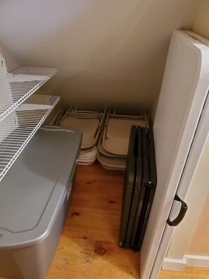 Et lille køkken med et køleskab, en vaskemaskine og stablede plastikbeholdere.